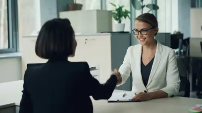 Recruiter shaking hands with candidate in a formal office setting